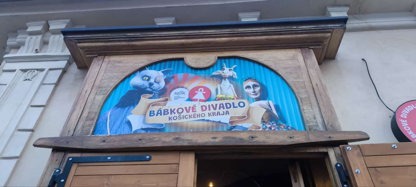 Vchod do bábkového divadla s dreveným portálom a plagátom